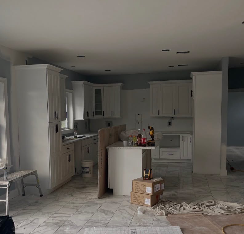 Kitchen remodel in progress with new cabinets installed and floors protected