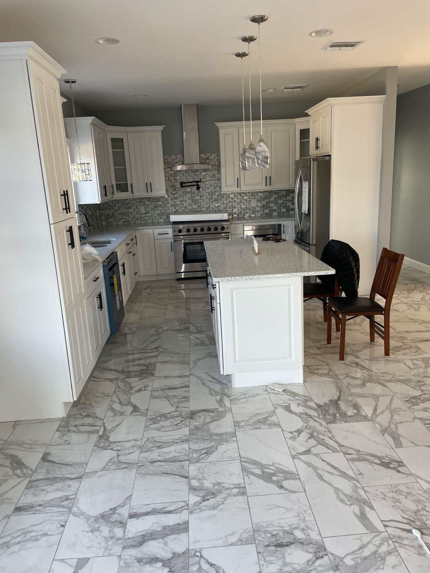Open kitchen remodel with tile backsplash, island seating and marble flooring