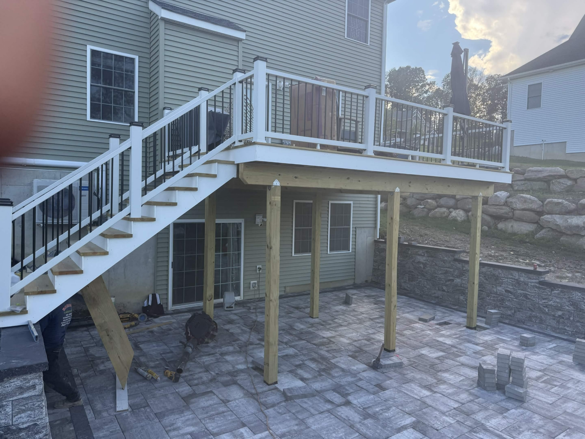 Paver patio installed beneath a deck with stone retaining edge
