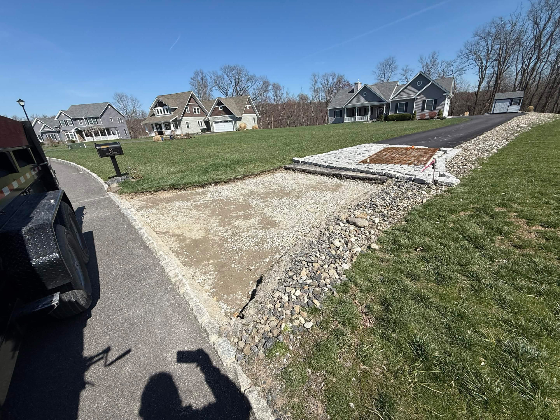 Stone-lined drainage swale running along a driveway
