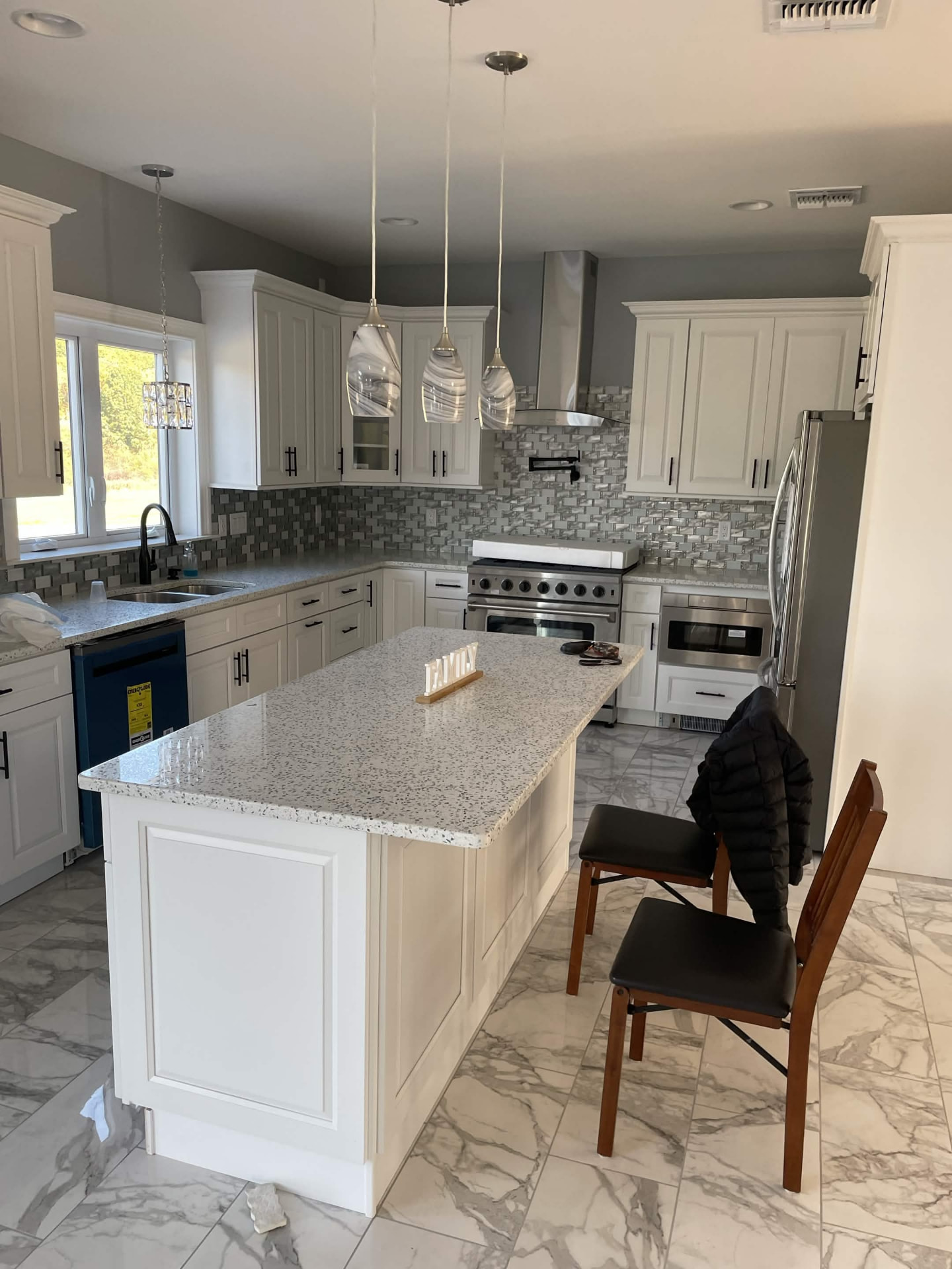 Remodeled kitchen with white cabinets, quartz island and marble tile floor